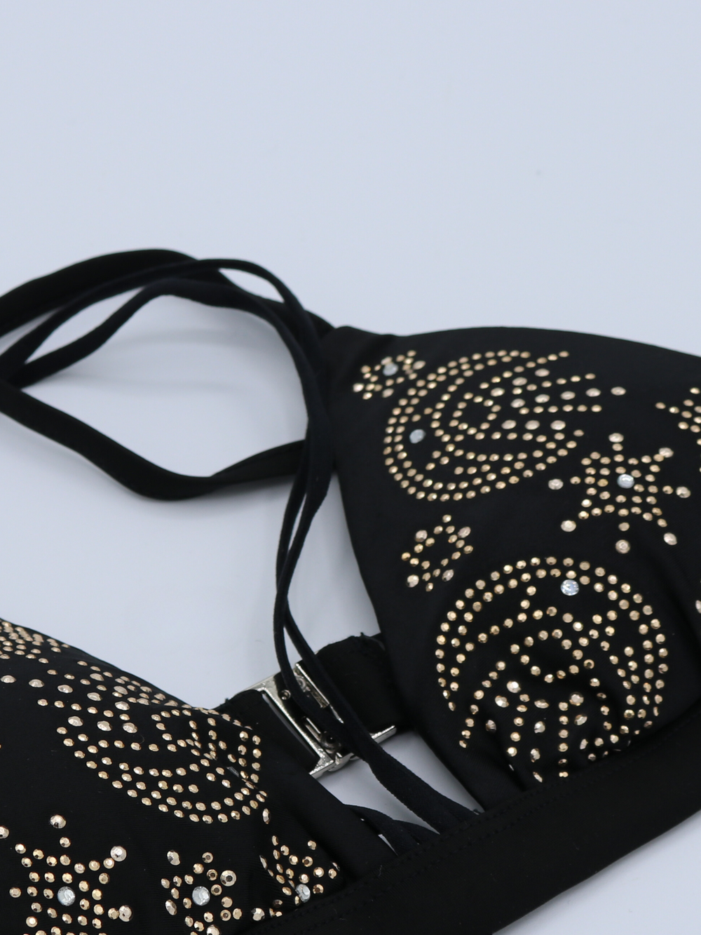 Closeup of black triangle bikini top with gold embelsihed studs and diamante detailing. The pattern on the bikini has cosmic designs. A statement and glamorous bikini.