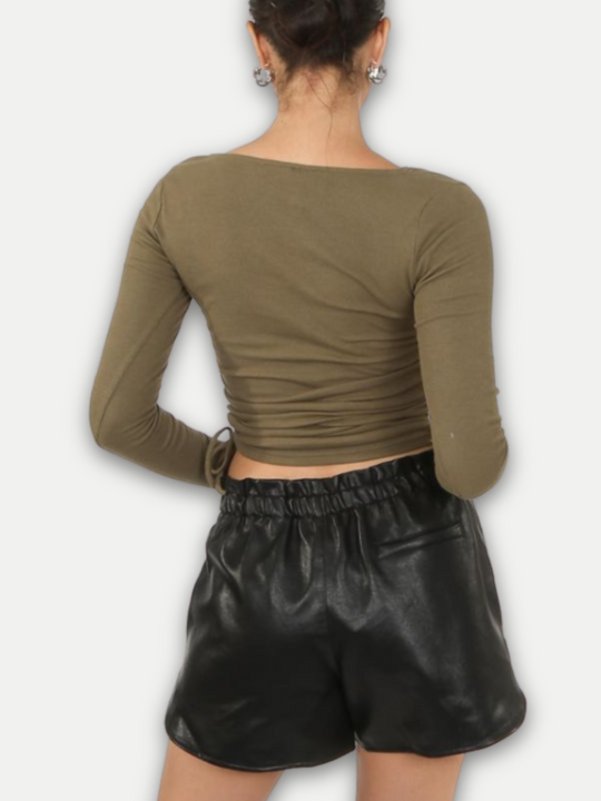  Model wears  pu leather running shorts, with front side pockets and a back pocket at the rear. The thick pu material demonstrates the high quality of the leather look shorts.  Model stands with her  back to the camera. The back of the faux leather shorts can be seen. 