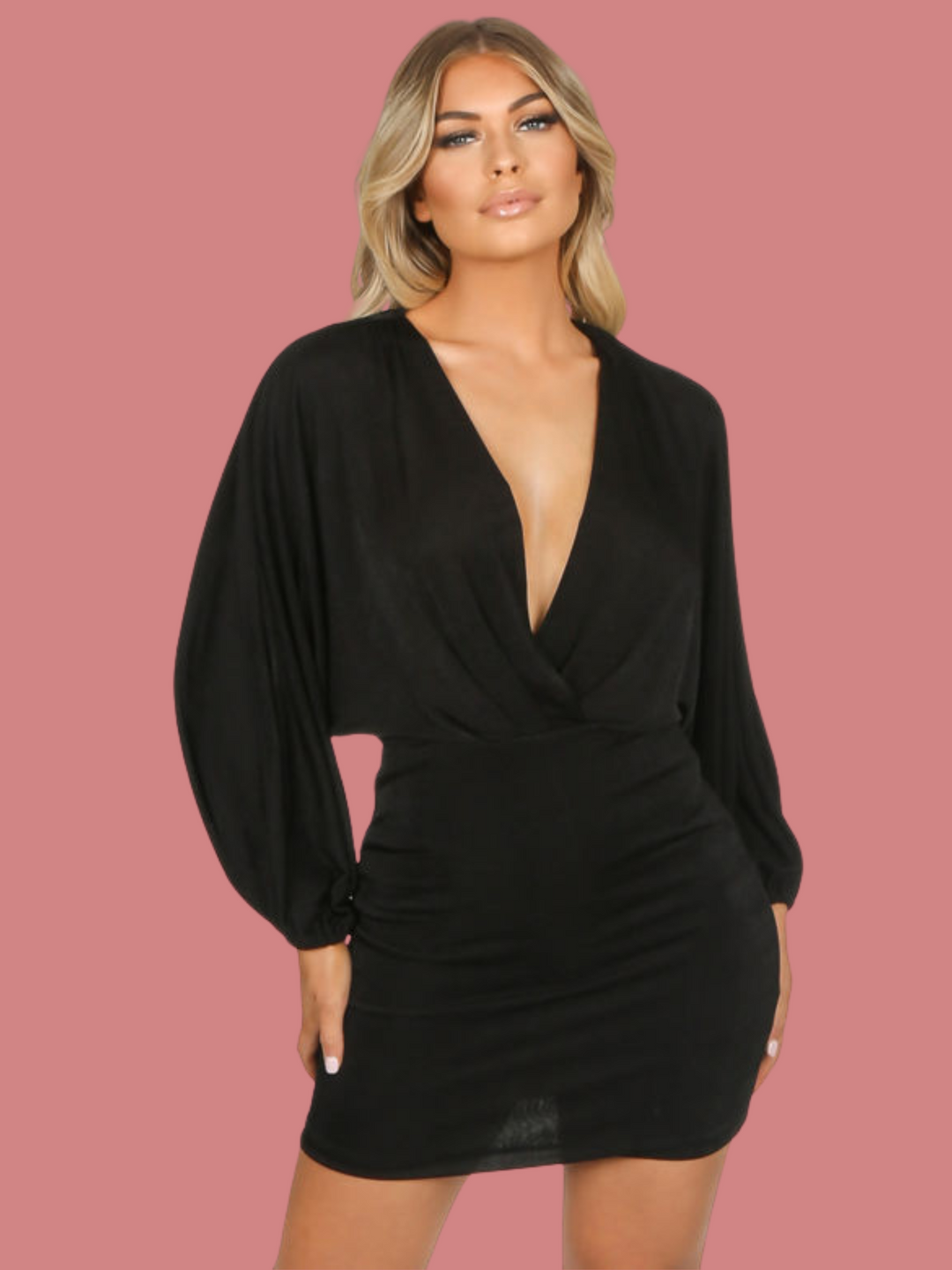 Model wears a black mini dress with adjustable plunging neckline, with long sleeved batwings. Model faces the camera with both her hands by her sides.