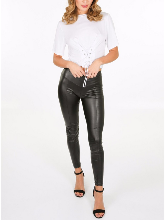 Whole body shot. Model wears a wet look, leather looking leggings with panelling. This faux leather leggings has a bodycon slim fit.  Model faces the camera, the front of the leggings can be seen.