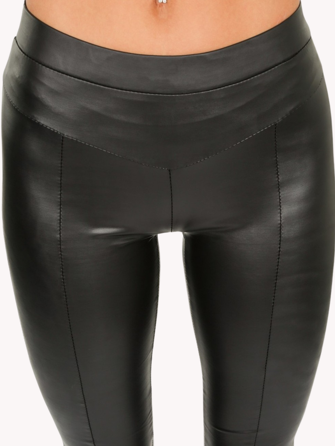 Model wears a wet look, leather looking leggings with panelling. This faux leather leggings has a bodycon slim fit. The closeup of the leggings can be seen.