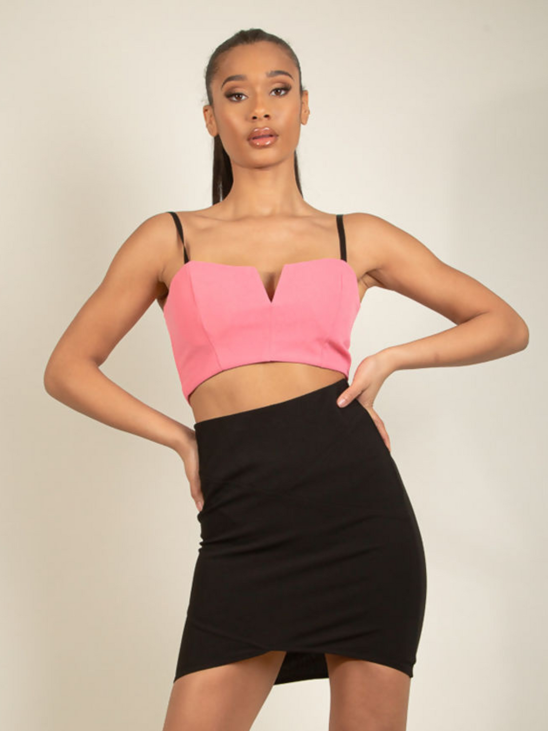 Model wears a black bandeau style wrap dress, with a bodycon midi fit with an elasticated waist. Model faces the camera with her hands on both hips.