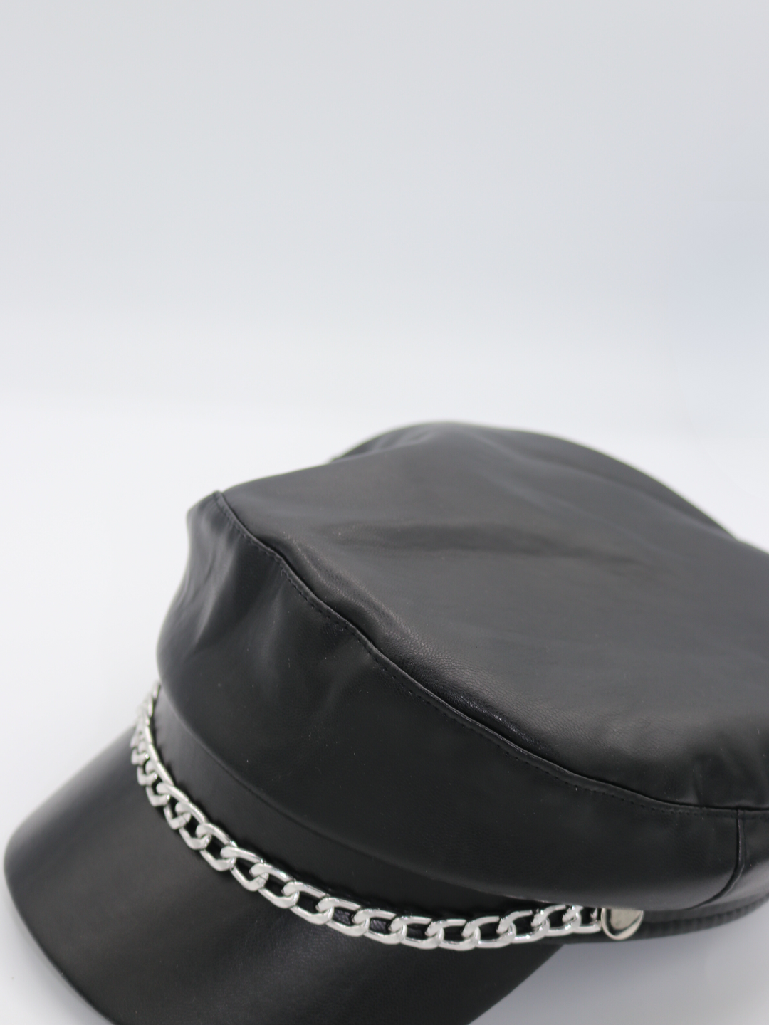 Side profile of the pu leather baker boy hat, demonstrating the front of the cap and the front silver detailing. 