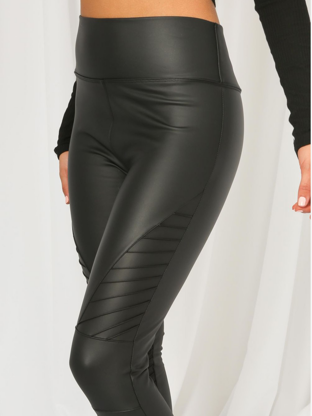 Model wears panelled high waisted leggings with a pu biker leggings design. Model stands to the side, the pu biker leggings is visible.