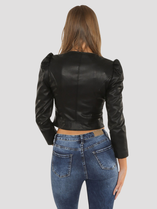 Model wears a leather look faux leather cropped jacket with puffed shoulders and long sleeves. Model stands and faces the camera with the jacket zipped up. Model stands with her back to the camera. The back of her jacket can be see, demonstrating the visible puffed sleeves and tailored fitted back of the jacket.