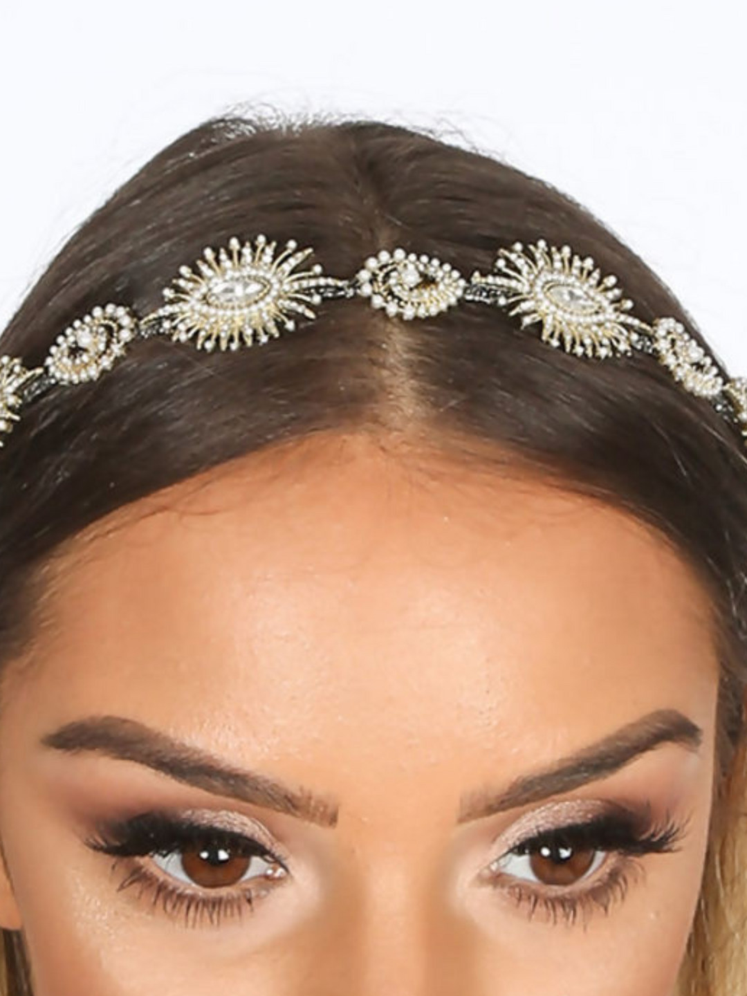 Close up of the gold metal hair band on models head. Model wears a metal head band in gold, the hair band has jewels and beaded design.