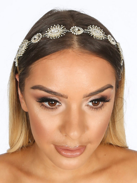 Model wears a metal head band in gold, the hair band has jewels and beaded design.