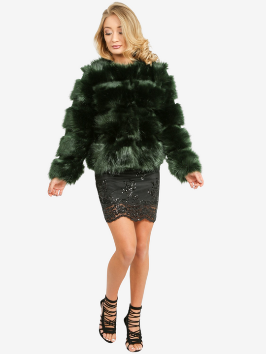 Model wears a soft faux fur long sleeve green jacket. The jacket has a front fastening and  satin like inner lining. Model wears the jacket closed, she is wearing a  black sequin dress.