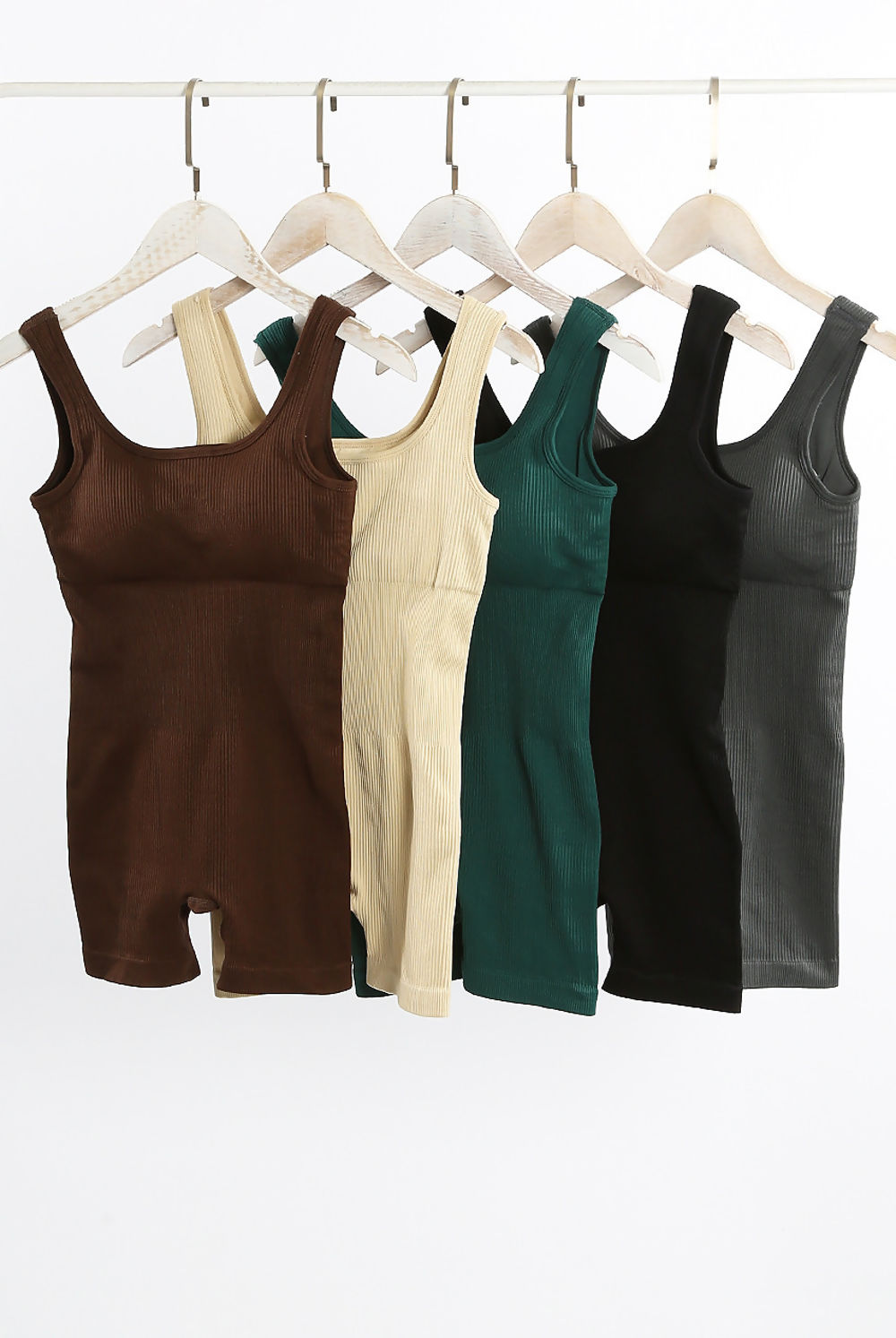 5 ribbed unitards handing on a pole. The colours of the unitard are: brown, cream, green, black and grey.