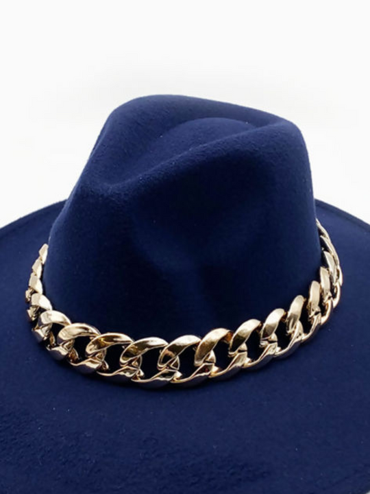 The front of th luxe navy felt fedora hat  with with chunky gold chain design  can be seen. The rich felt navy blue colour is visible and compliments the chunky gold chain detailing well. 