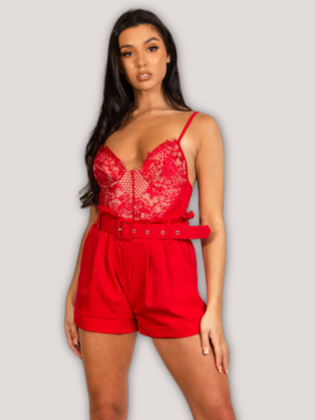 Model wears a red bodysuit with lace panel detailing. Model stands with her hands to the side and one leg outstretched. 