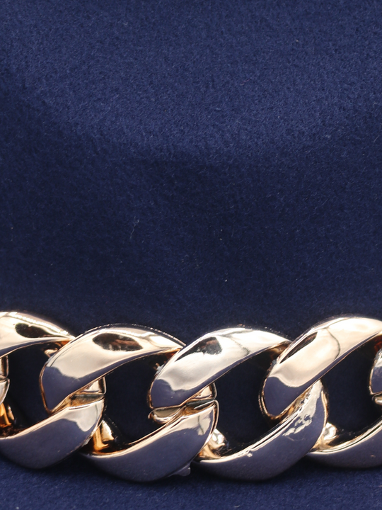 Close up of chunky gold linked detailing and blue felt  material of the fedora hat.